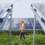 Man worker in the firld by the solar panels