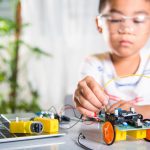 nino-asiatico-que-conecta-energia-cable-senal-al-chip-sensor-coche-robot-arduino_143683-4523